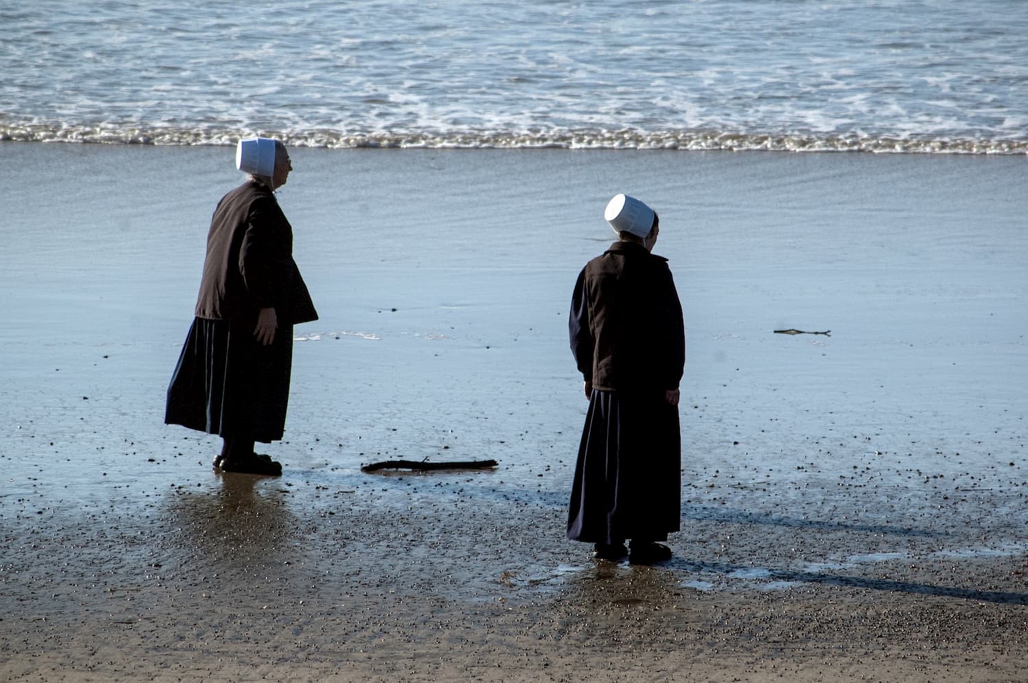 Photograph by Tish Lampert showing two Nuns standing on the beach