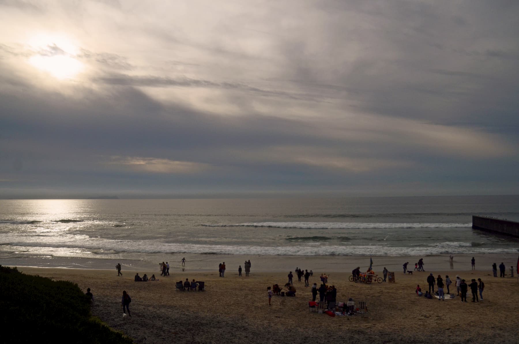 Photograph by Tish Lampert depicting a sunset at the beach in Tijuana. Several people are walking along the water